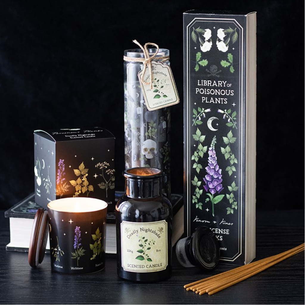 Gothic-themed candles, bottles, and books on a dark surface with a black background