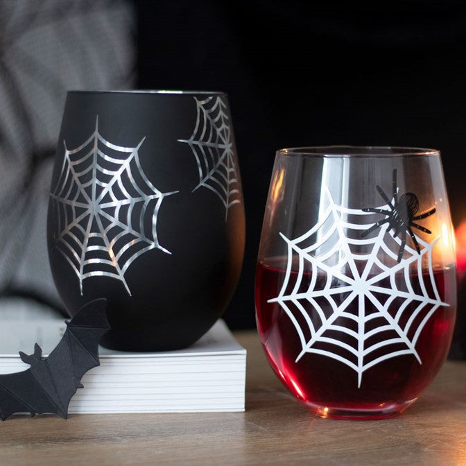 Two stemless wine glasses with spider web designs on a wooden surface.