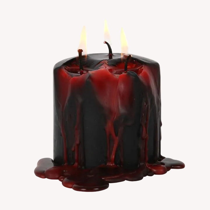 Black candle with red wax dripping on a white background