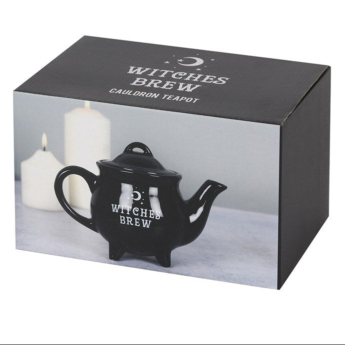 Black 'Witches Brew' cauldron teapot in packaging with candles on a white background