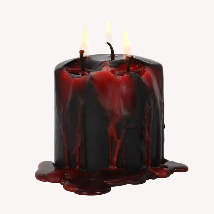 Black candle with red wax dripping on a white background