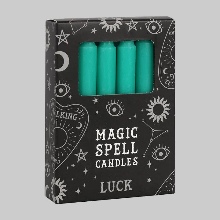 Pack of teal candles labeled 'Magic Spell Candles Luck' with astrological symbols on a black background.