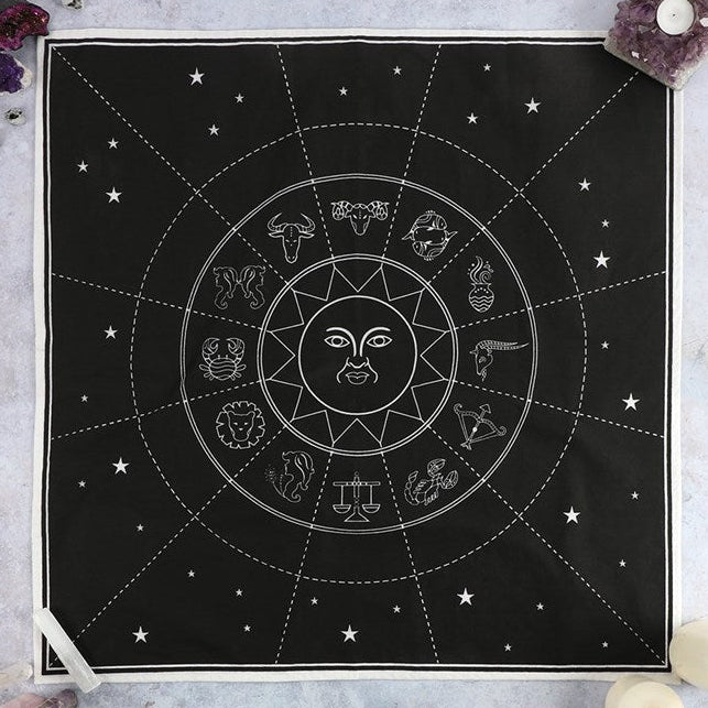 Black tapestry with white astrological symbols and designs on a gray surface.