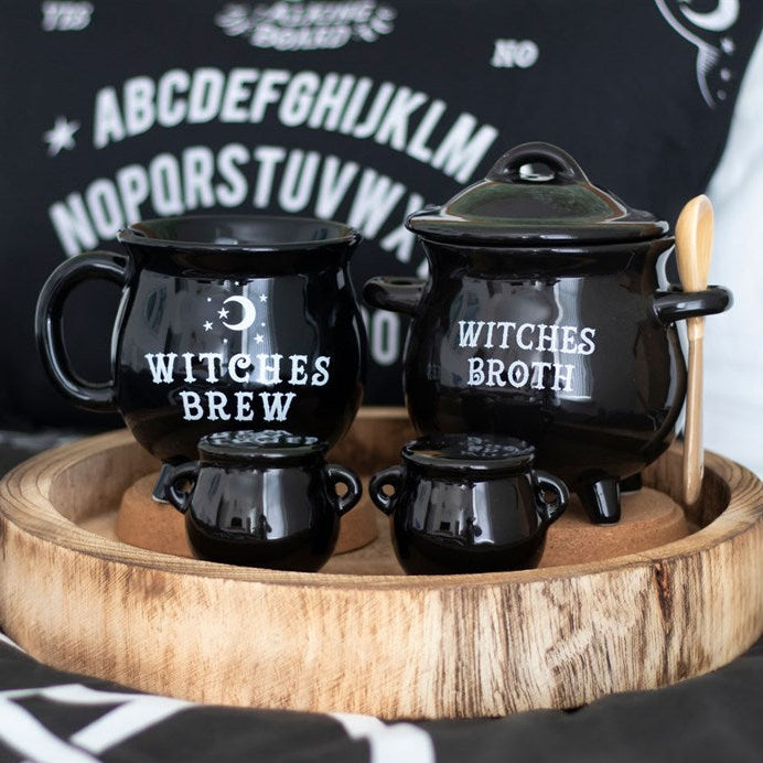 Black ceramic pot and mugs with 'Witches Brew' and 'Witches Broth' text on a wooden tray.
