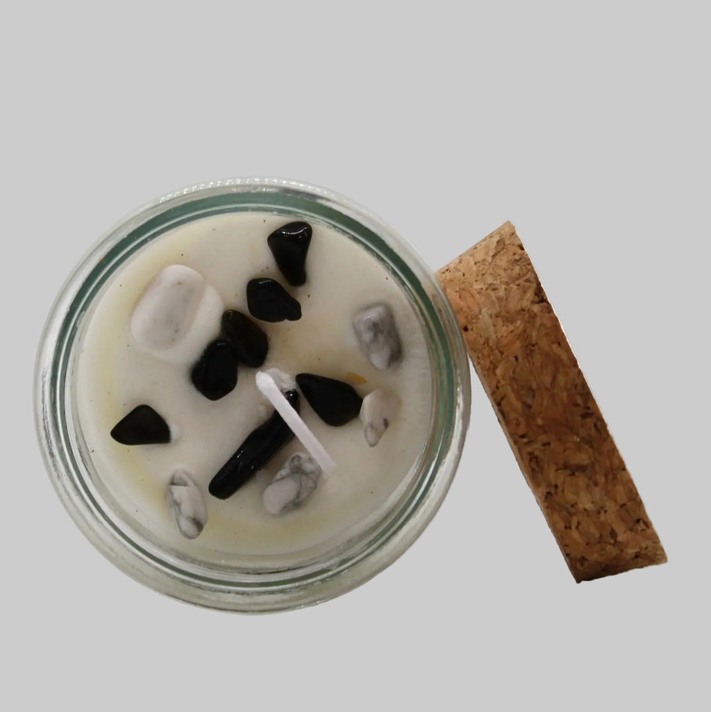 Candle in a glass jar with decorative stones on a white background