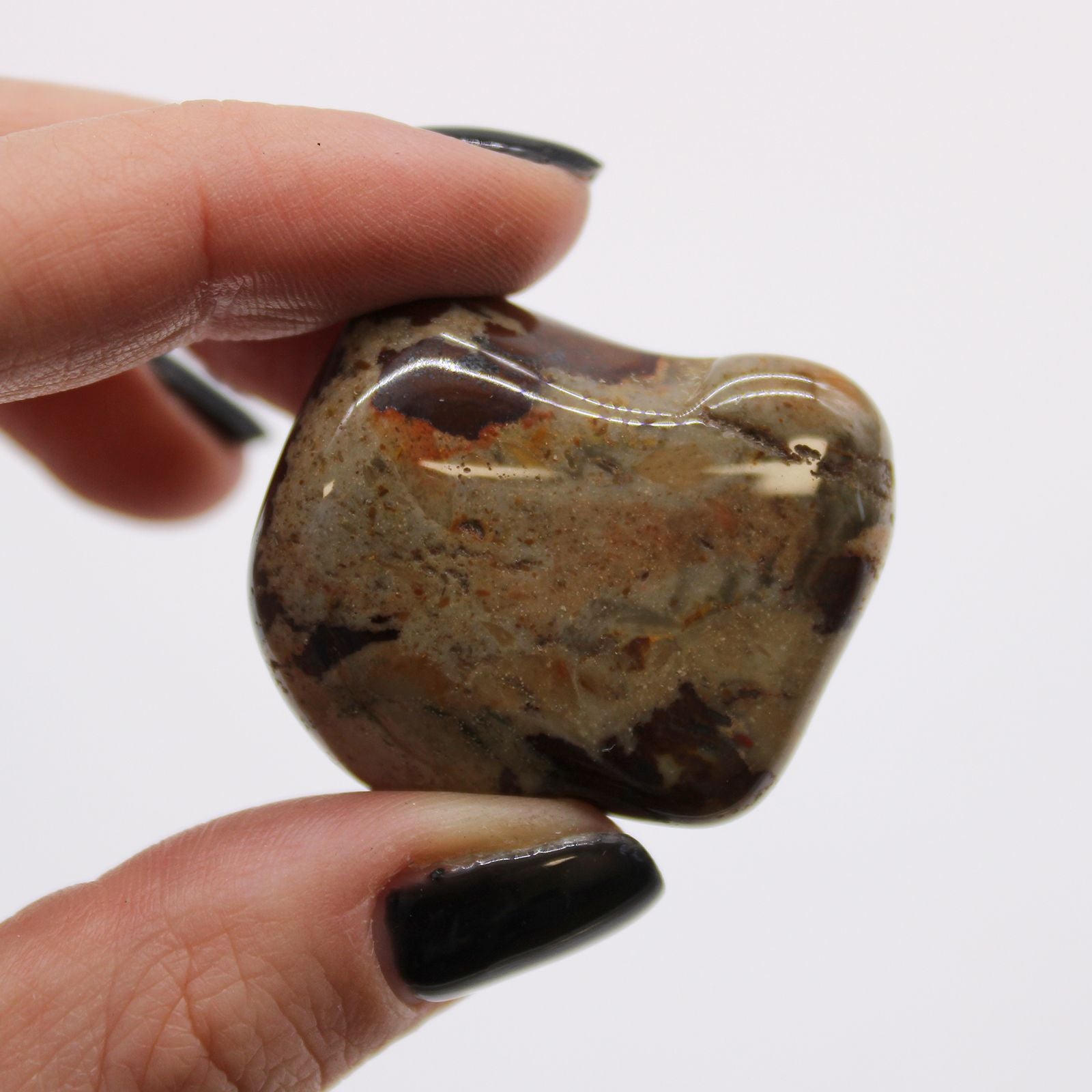 Hand holding a polished stone against a white background