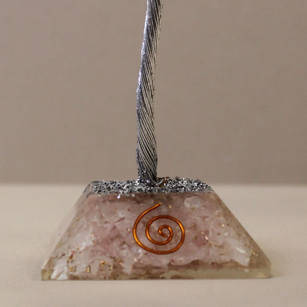 Pyramid-shaped object with metallic top and spiral design on a beige background