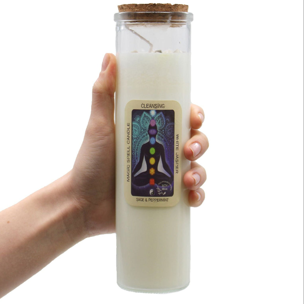 Hand holding a white candle in a glass jar with a label on a white background