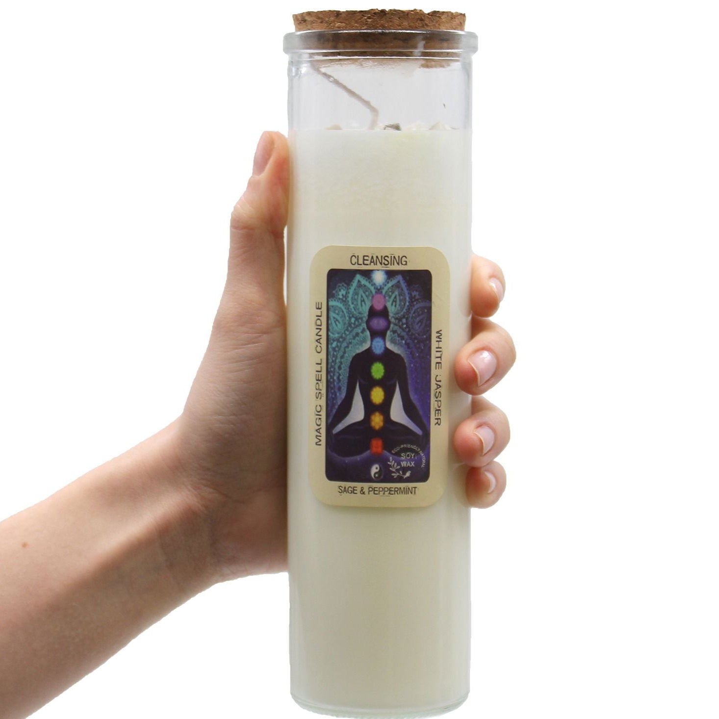 Hand holding a white candle in a glass jar with a label on a white background