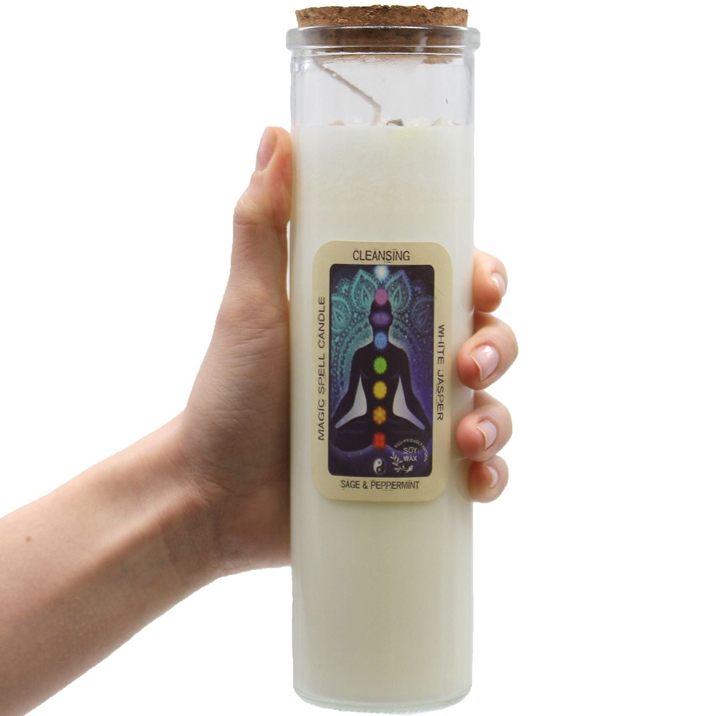 Hand holding a white candle in a glass jar with a label on a white background