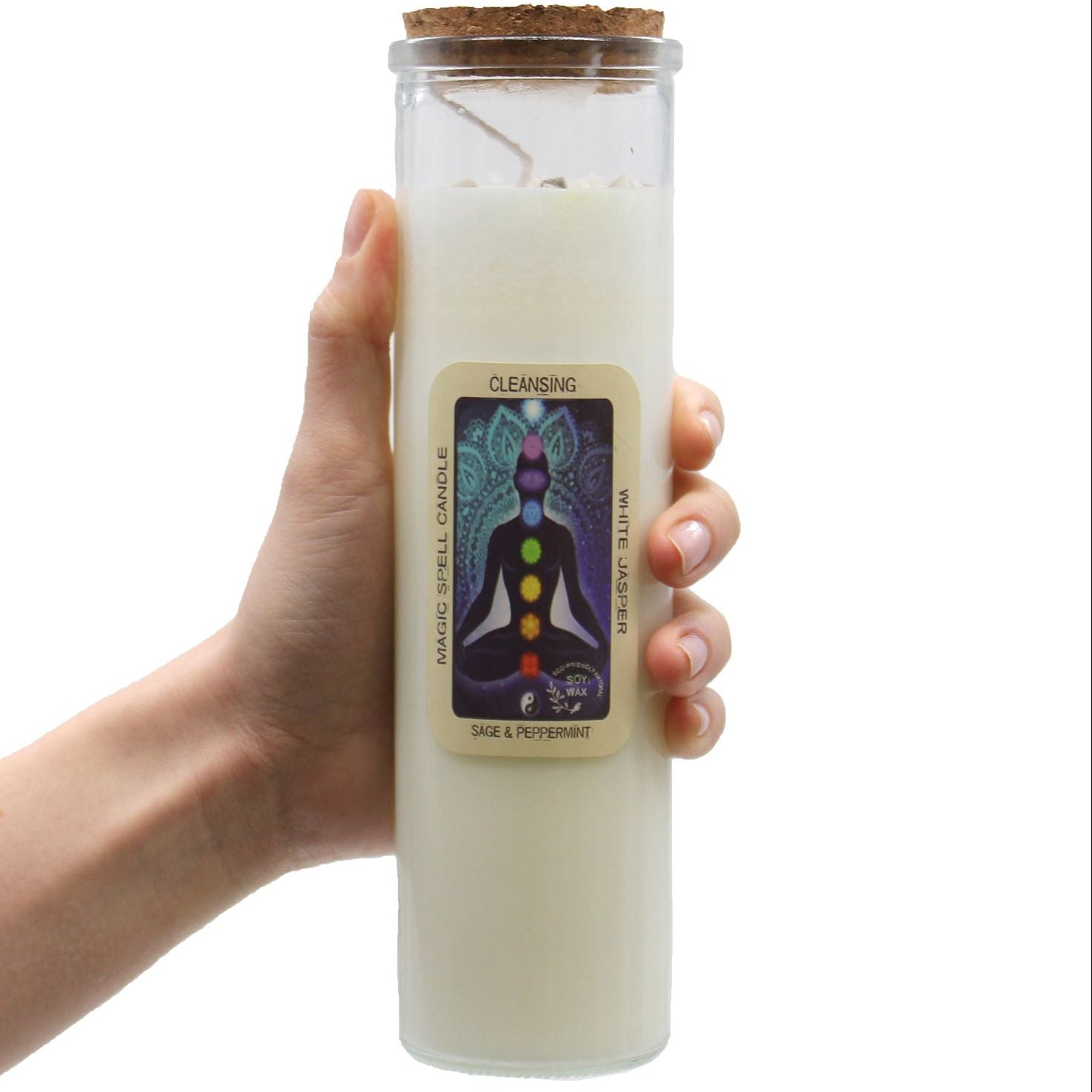 Hand holding a white candle in a glass jar with a label on a white background