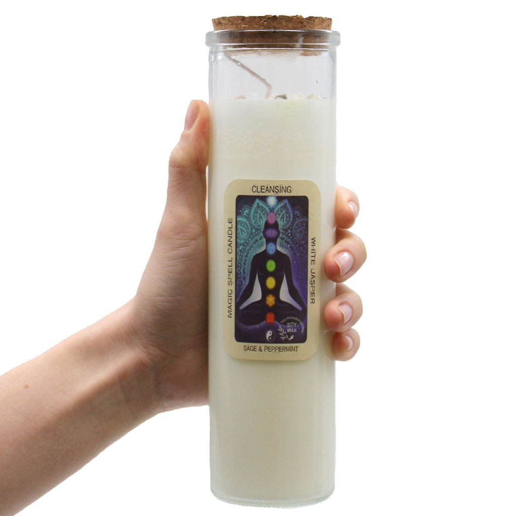 Hand holding a white candle in a glass jar with a label on a white background