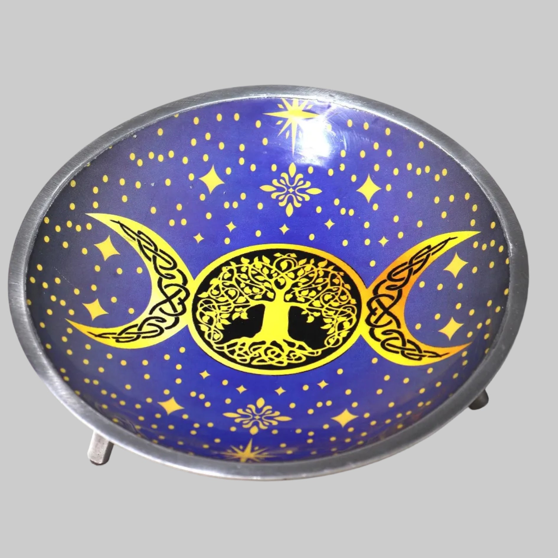 Decorative plate with tree of life and moon phases design on a blue background with stars.