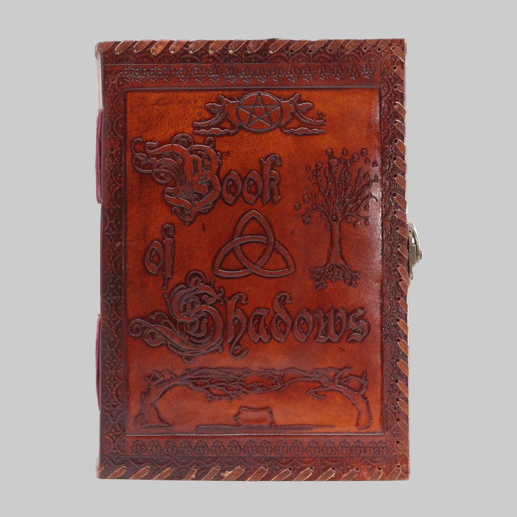 Brown leather book titled 'Book of Shadows' with embossed designs on a white background