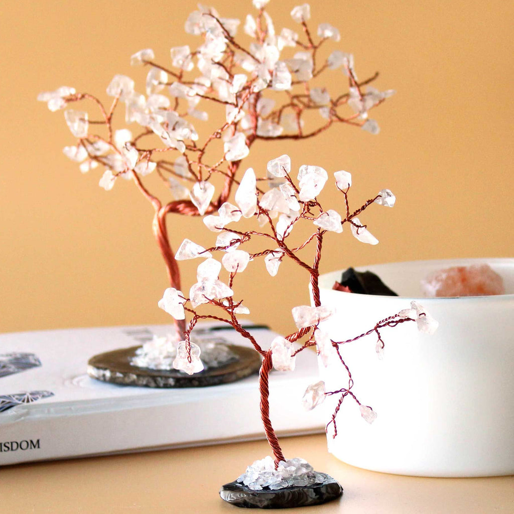Decorative tree with white flowers on a desk with a book and mug in the background