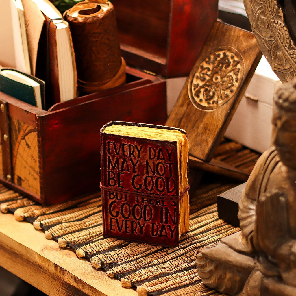 Decorative wooden book with motivational quote on a wooden surface with a Buddha statue.