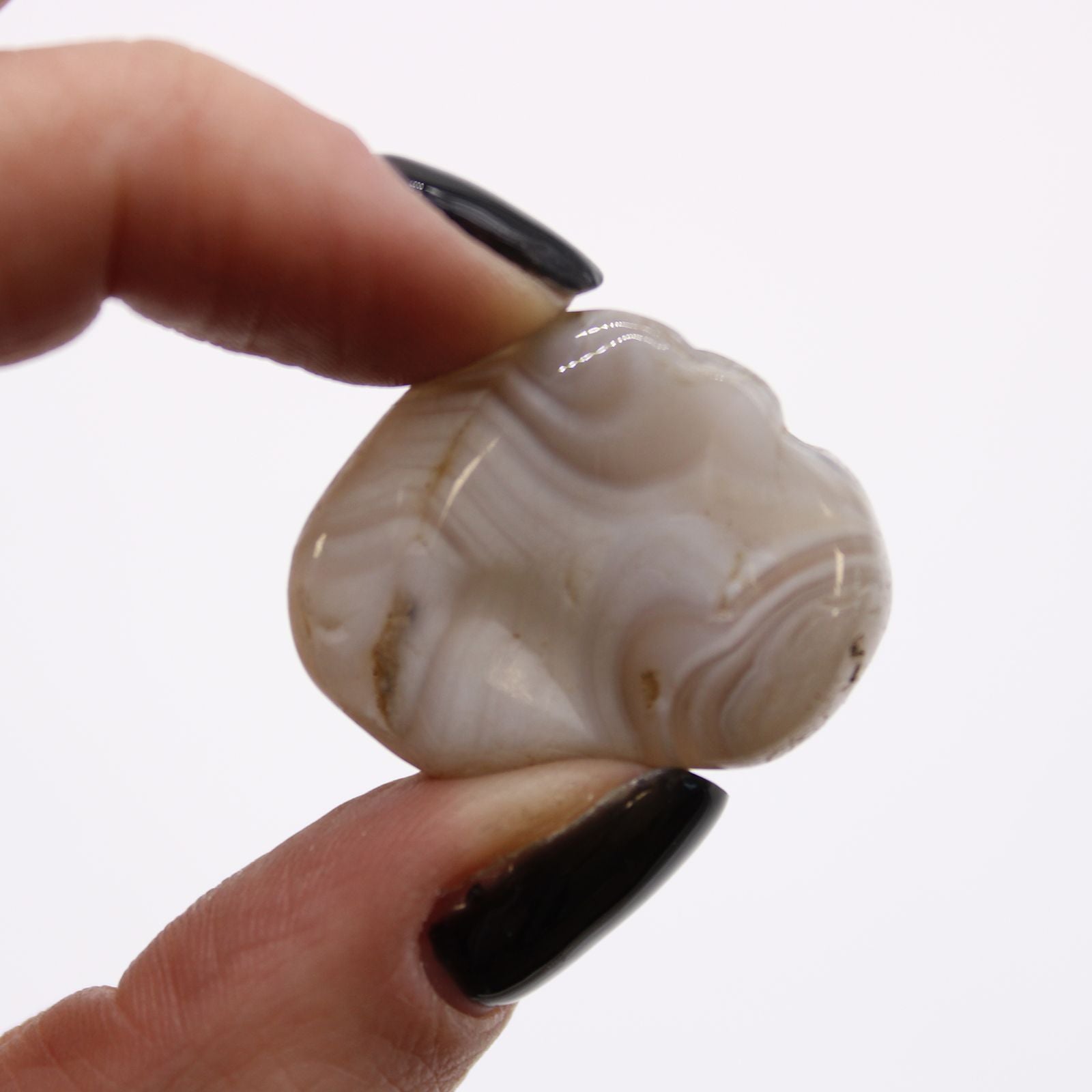 Hand holding a marbled stone with intricate patterns on a white background