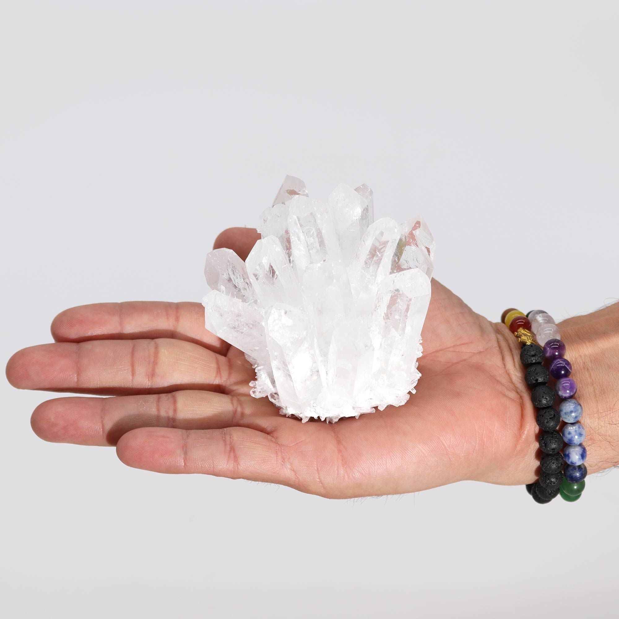 Hand holding a small crystal formation against a plain background