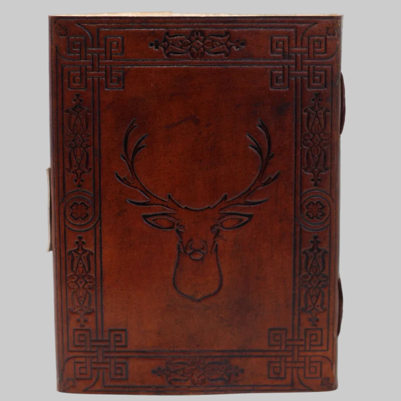 Brown leather notebook with deer head design and intricate patterns on a white background