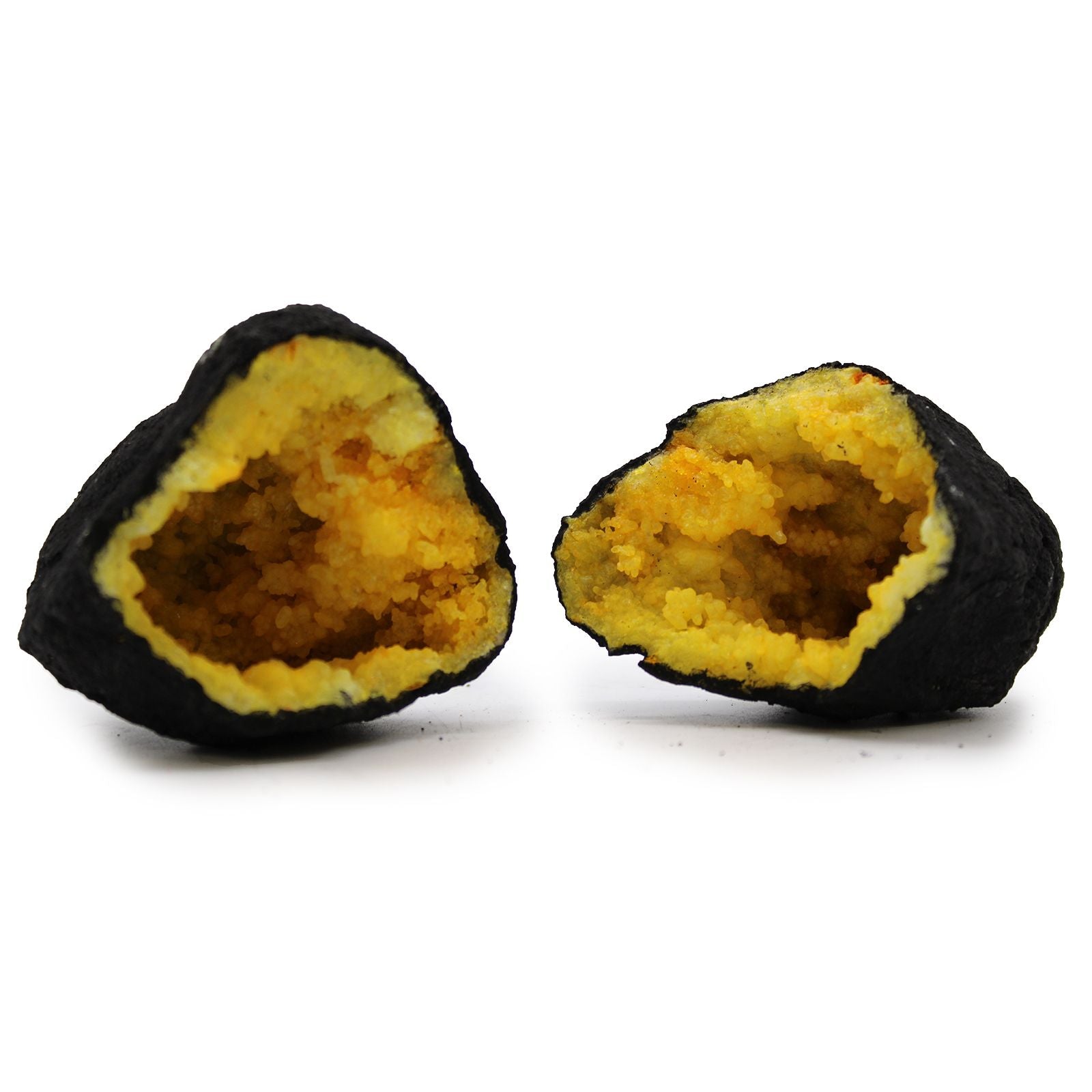 Two split open black and yellow truffles on a white background