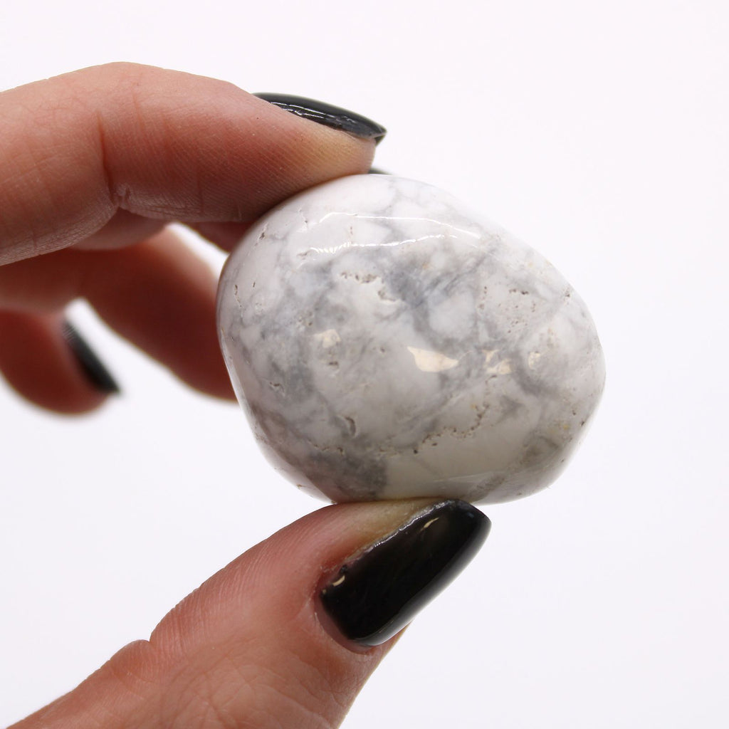 Hand holding a white and gray marbled stone against a white background