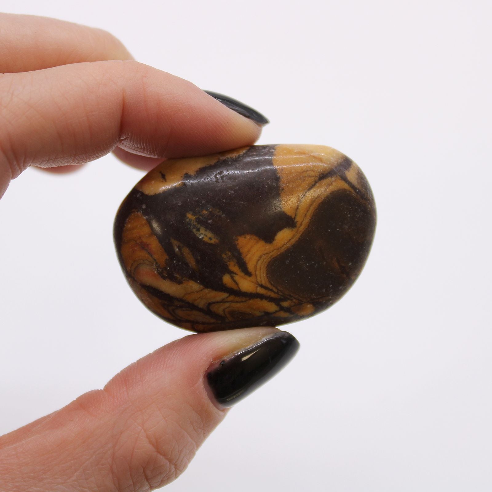 Hand holding a marbled stone against a white background