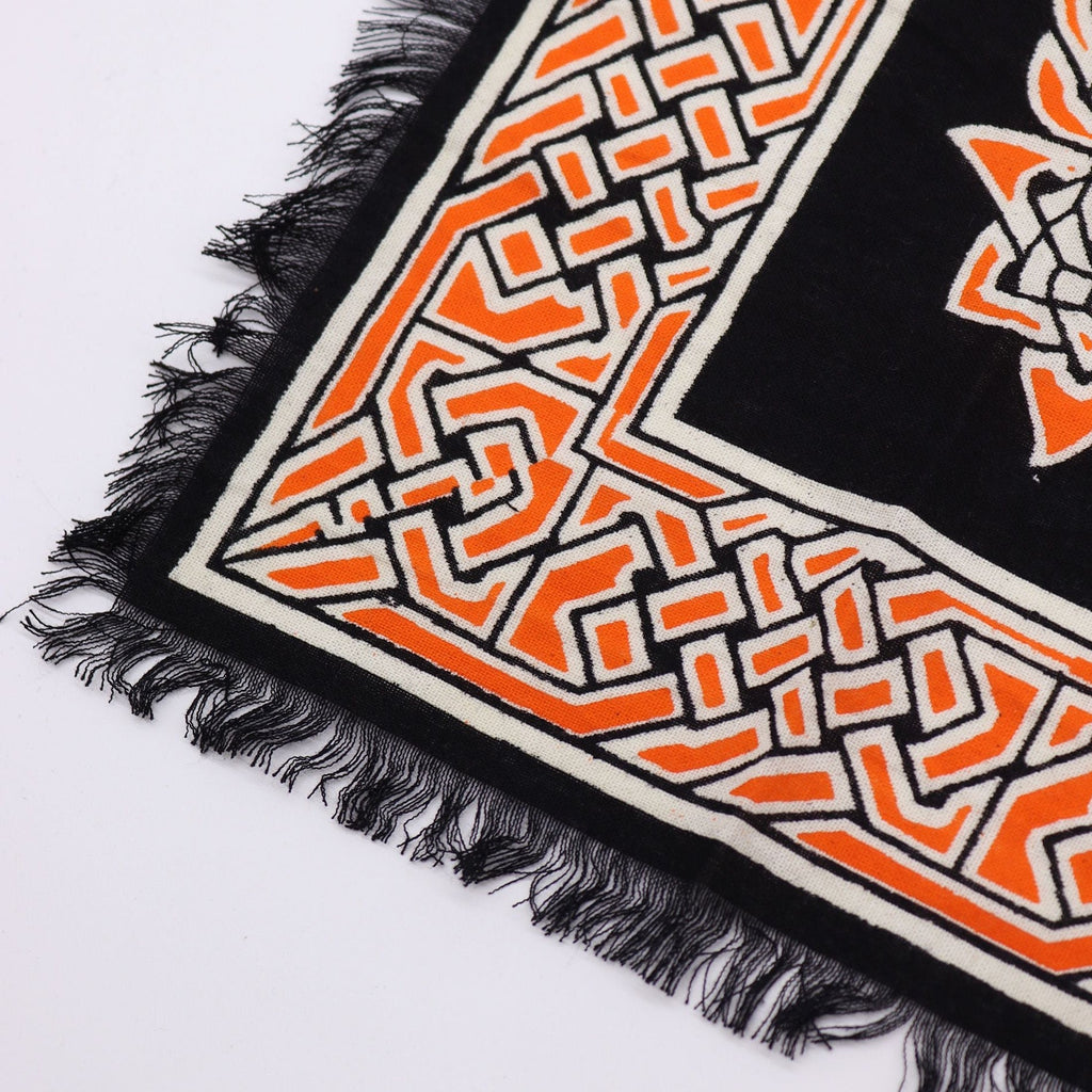 Close-up of a patterned fabric with orange and black design on a white background