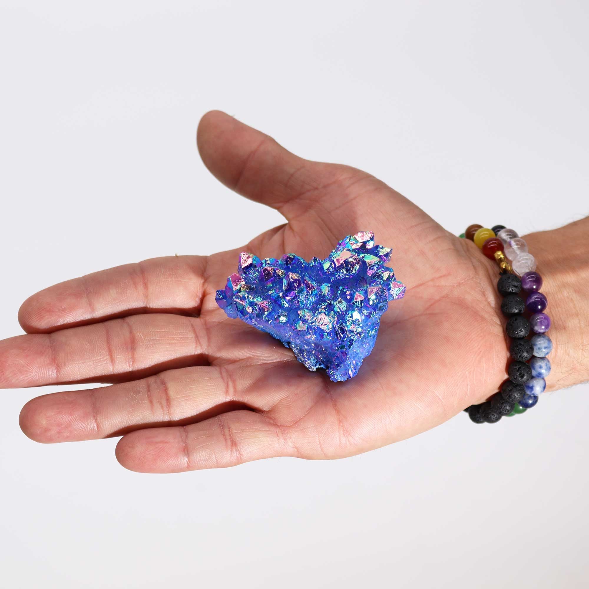 Hand holding a blue crystal formation with a white background