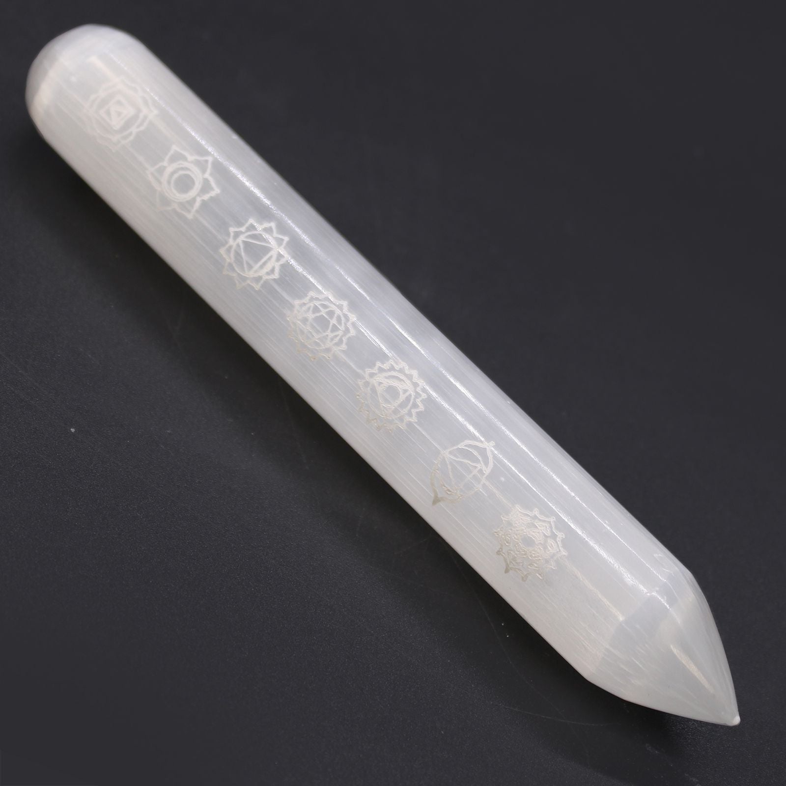 White crystal wand with engraved symbols on a black background