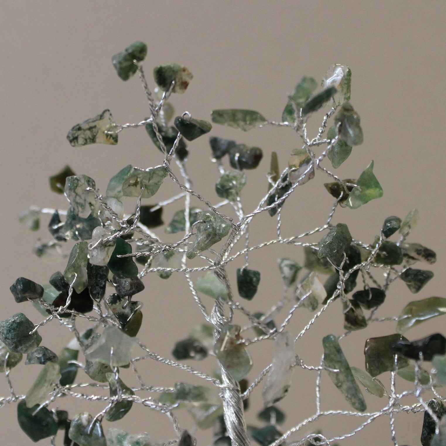 Decorative branch with green leaves and silver wire on a beige background