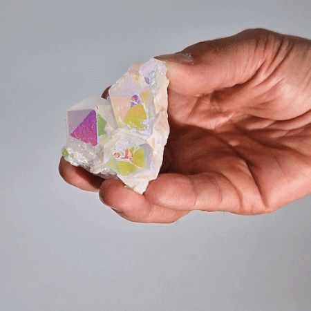 Hand holding a crystal with colorful labels against a gray background