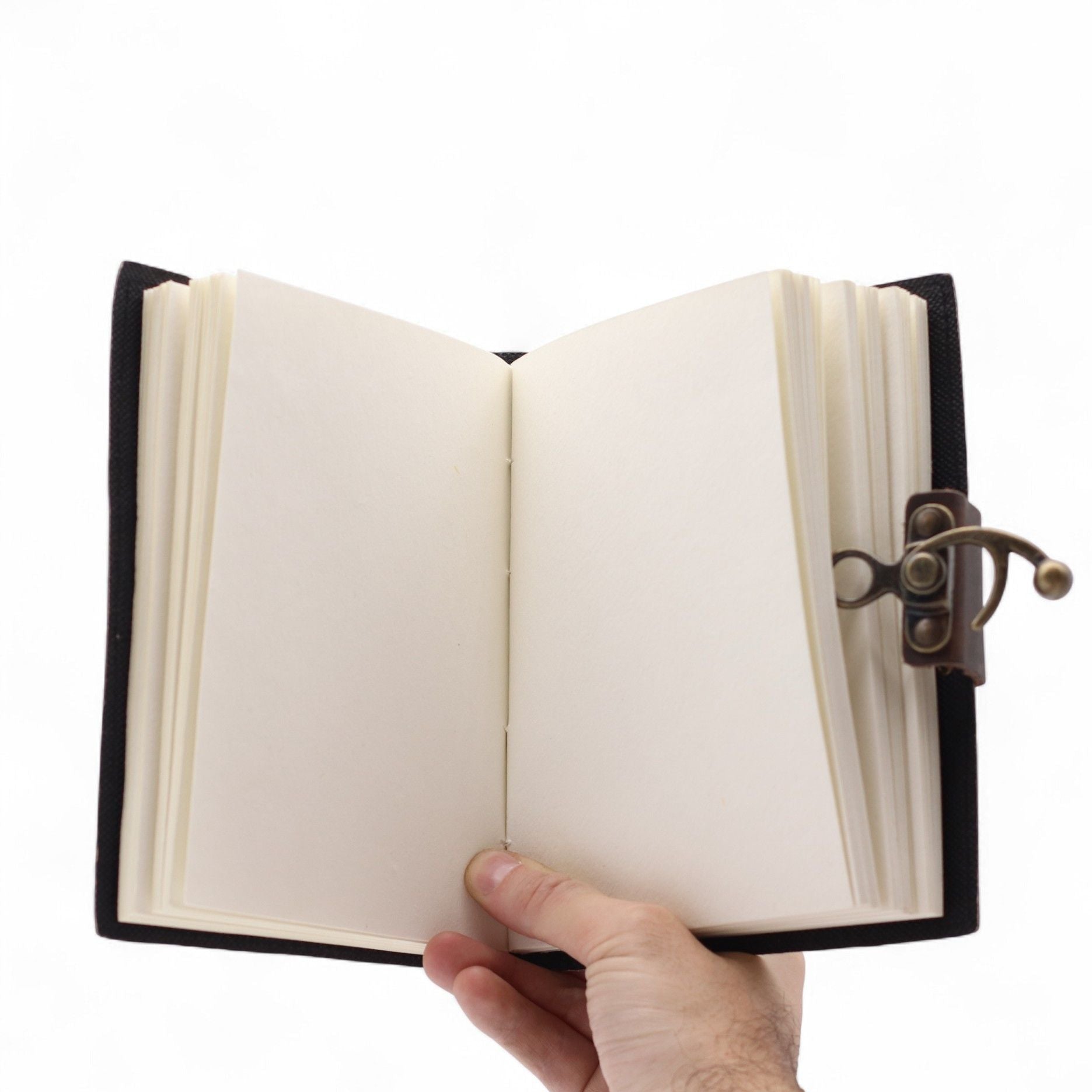 Hand holding an open notebook with a black leather cover on a white background