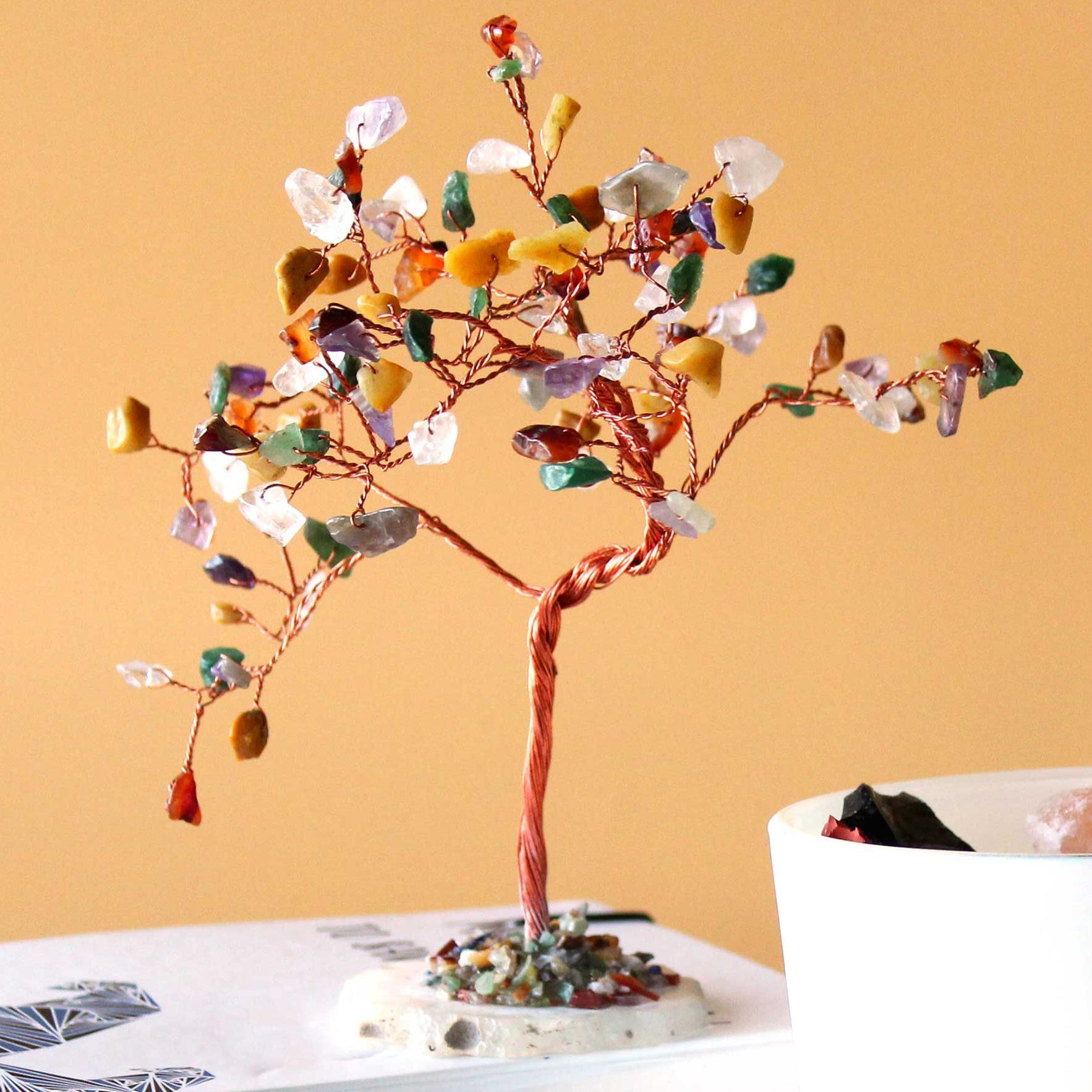Decorative tree with colorful beads on a book against a beige background