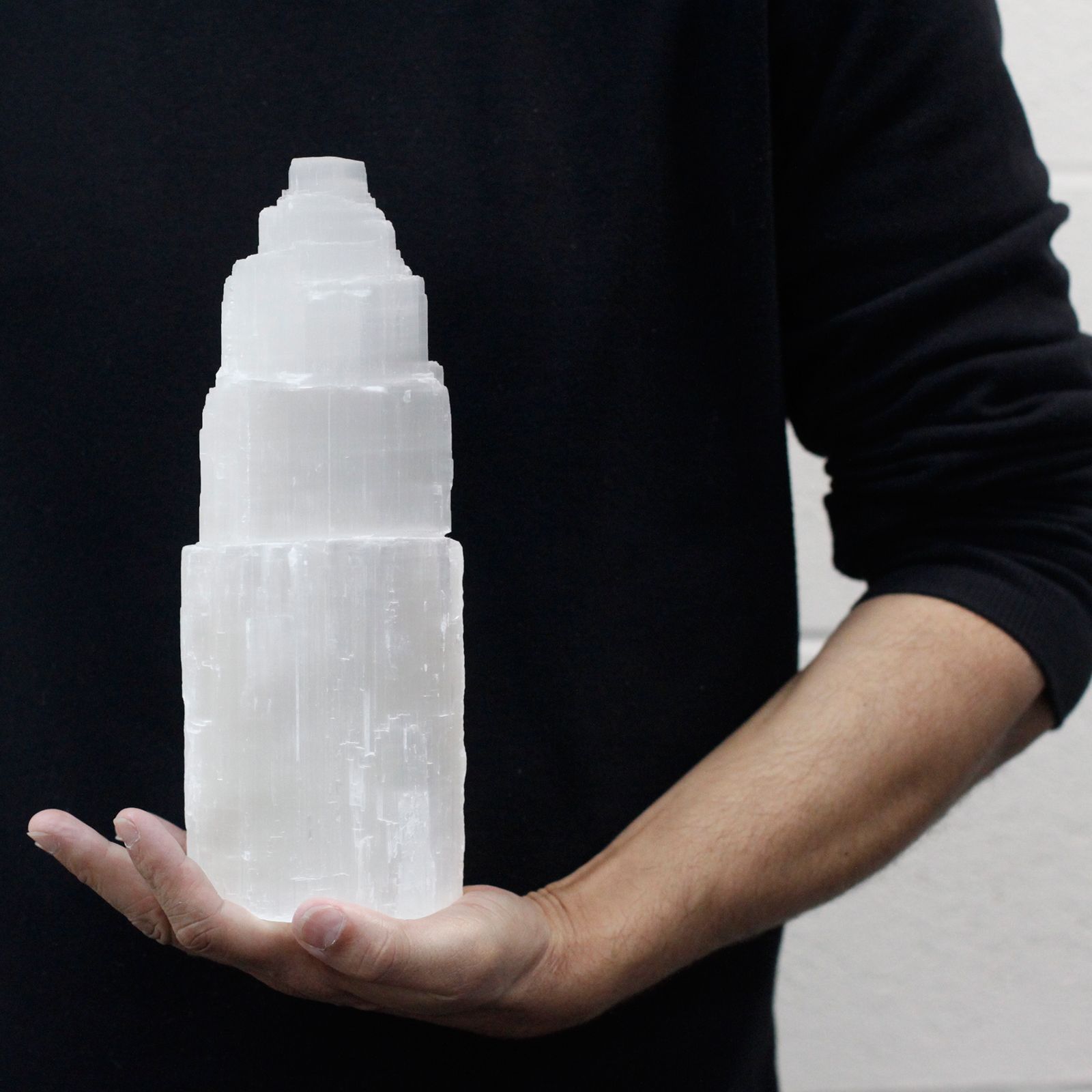 Person holding a large crystal tower against a black background