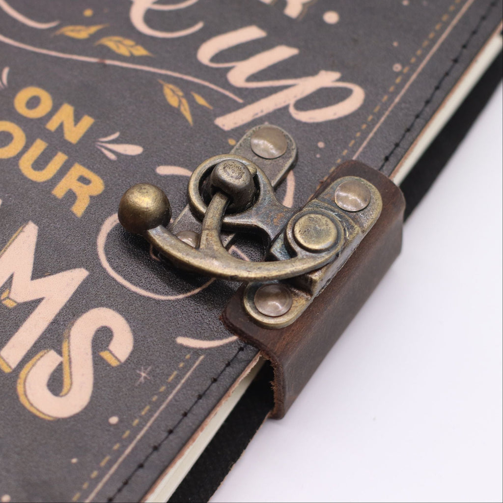 Close-up of a decorative latch on a leather-bound book with text in the background.
