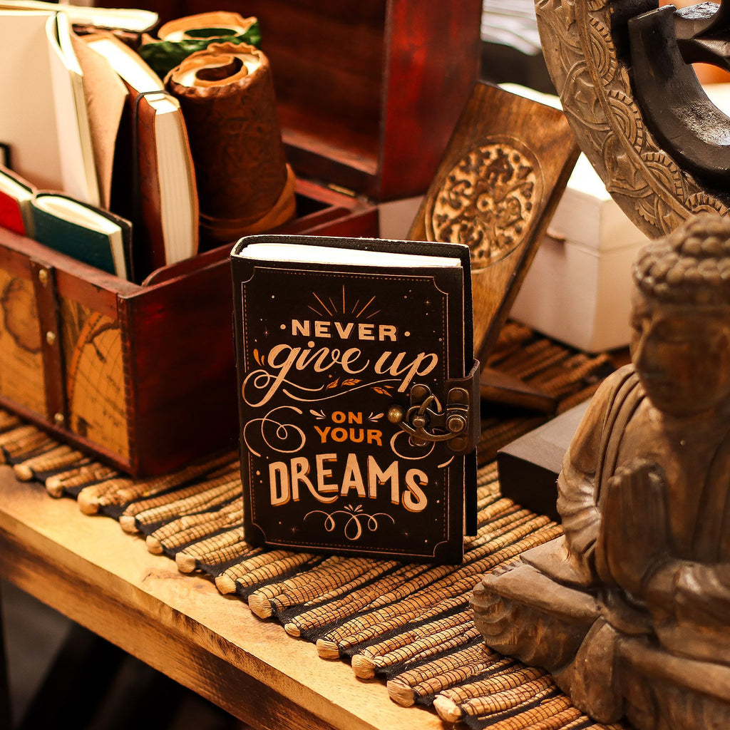 Small book with 'Never give up on your dreams' quote on a wooden surface with decorative items.