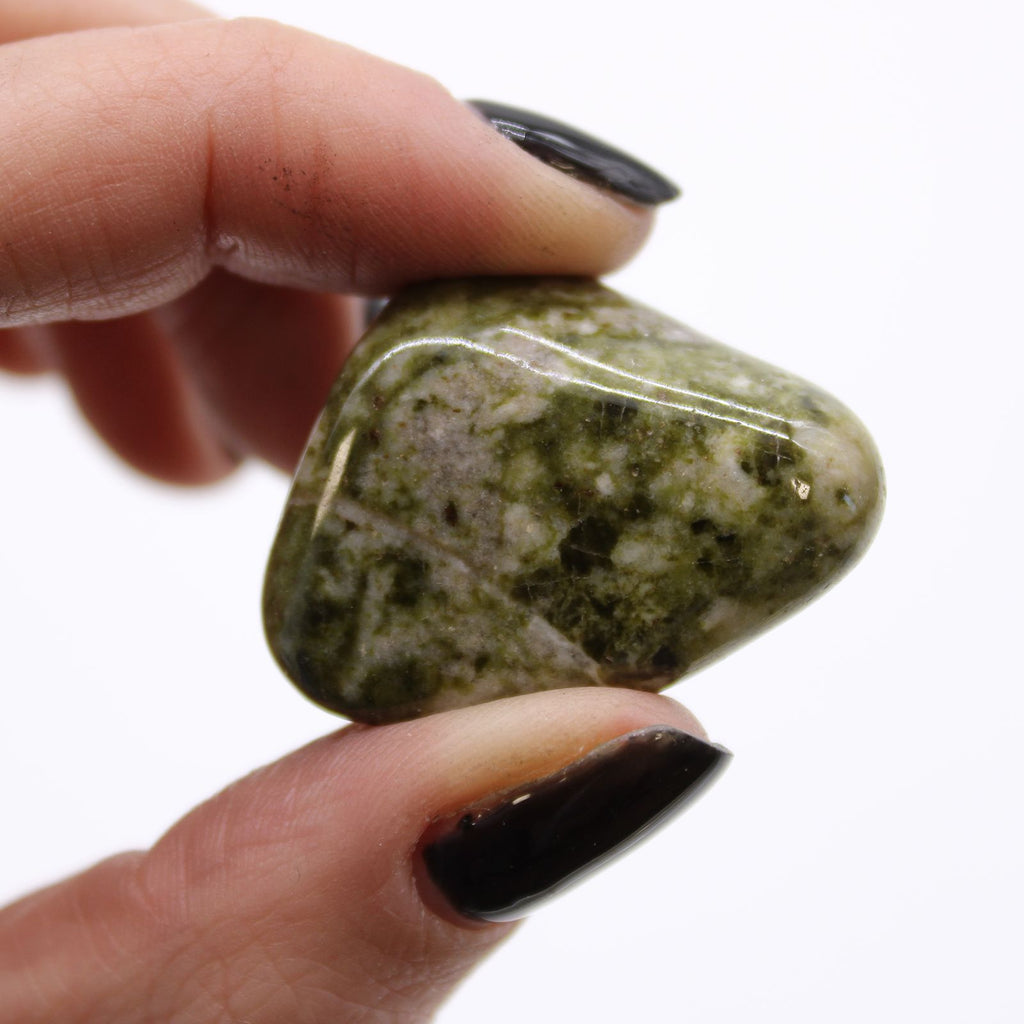 Hand holding a green stone against a white background