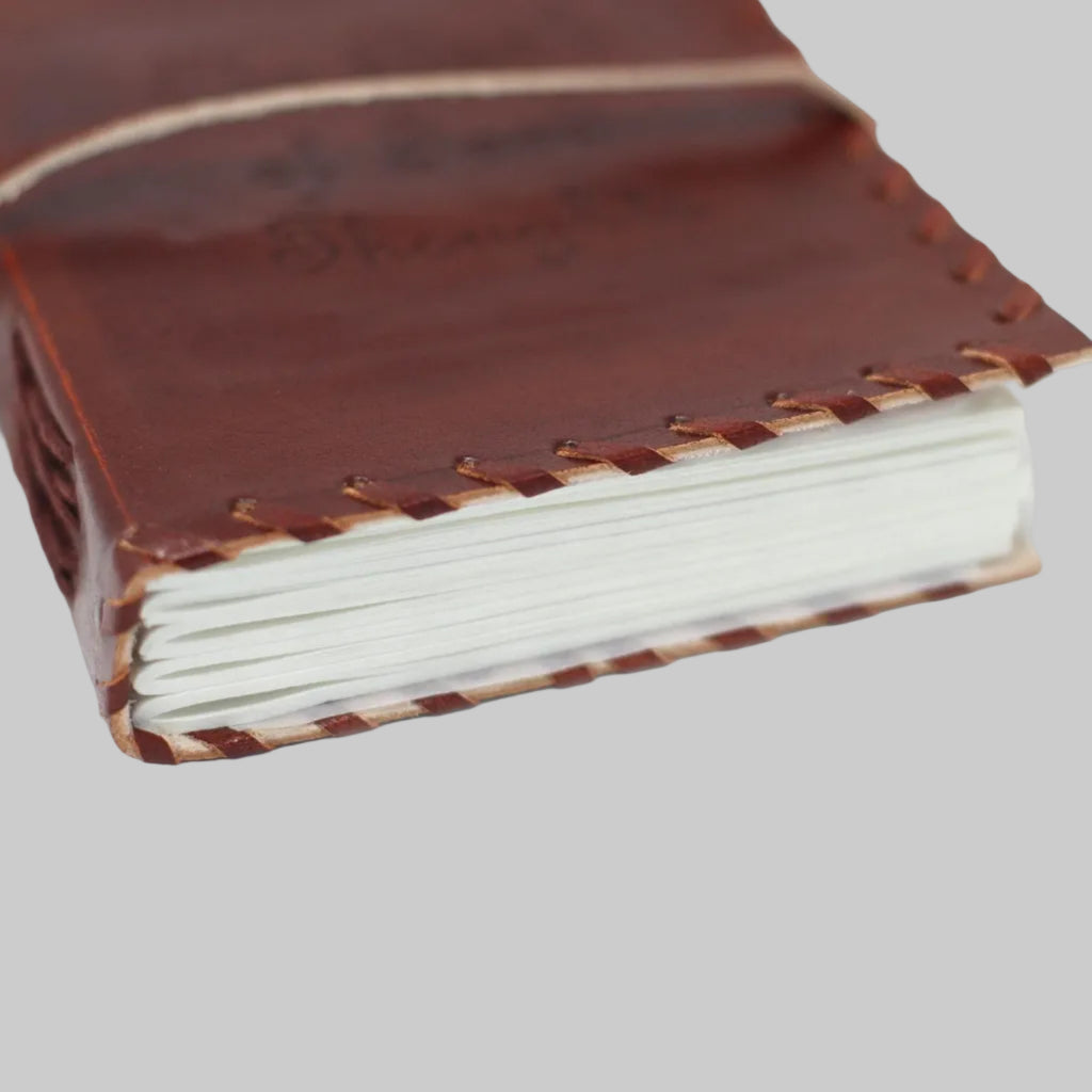 Brown leather notebook with white pages on a white background