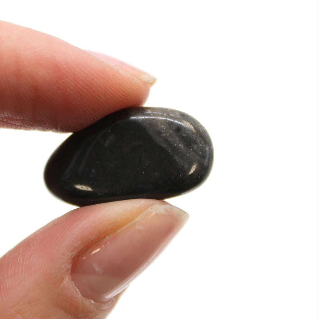 Hand holding a small black stone against a white background