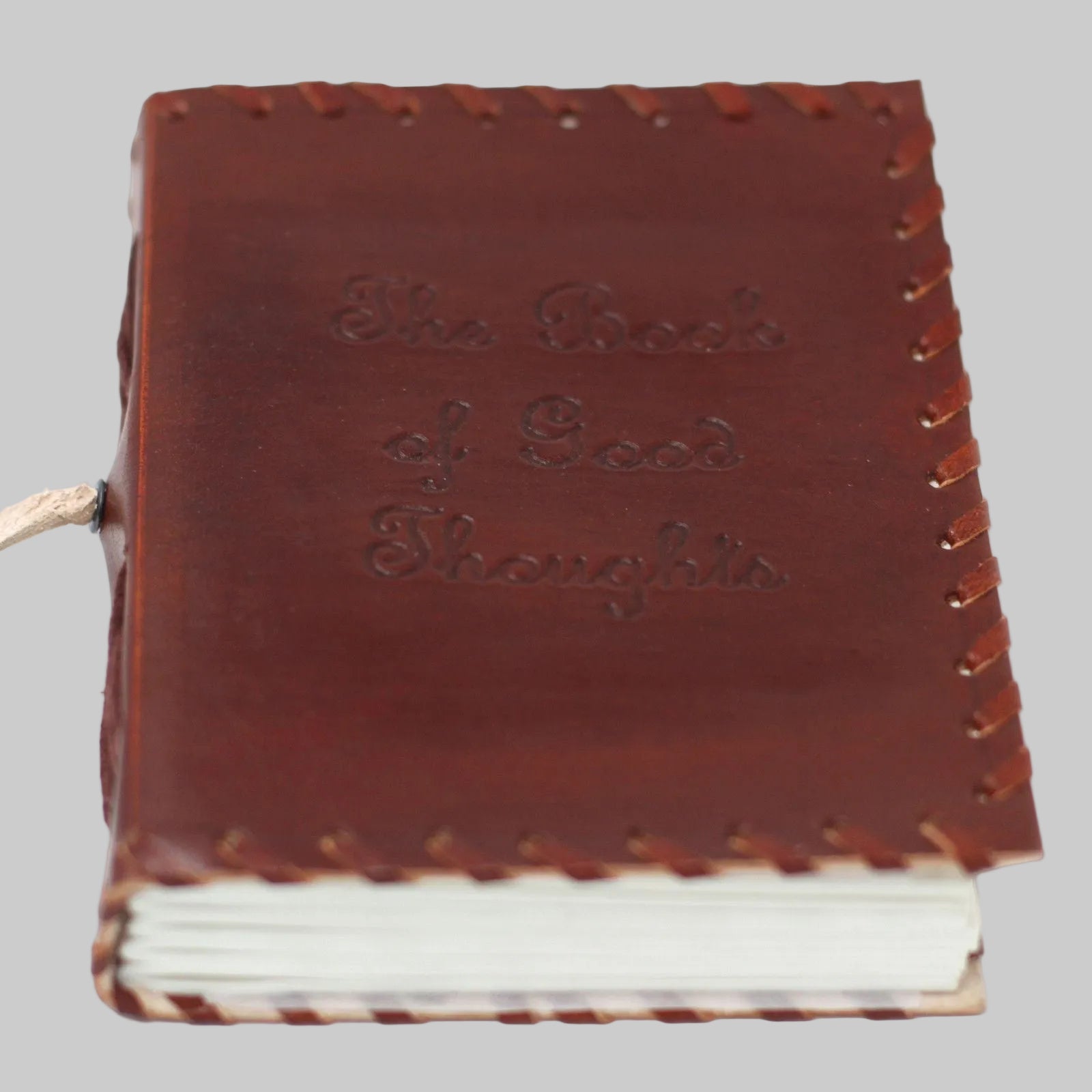 Brown leather notebook with 'Book of Good Thoughts' embossed on the cover