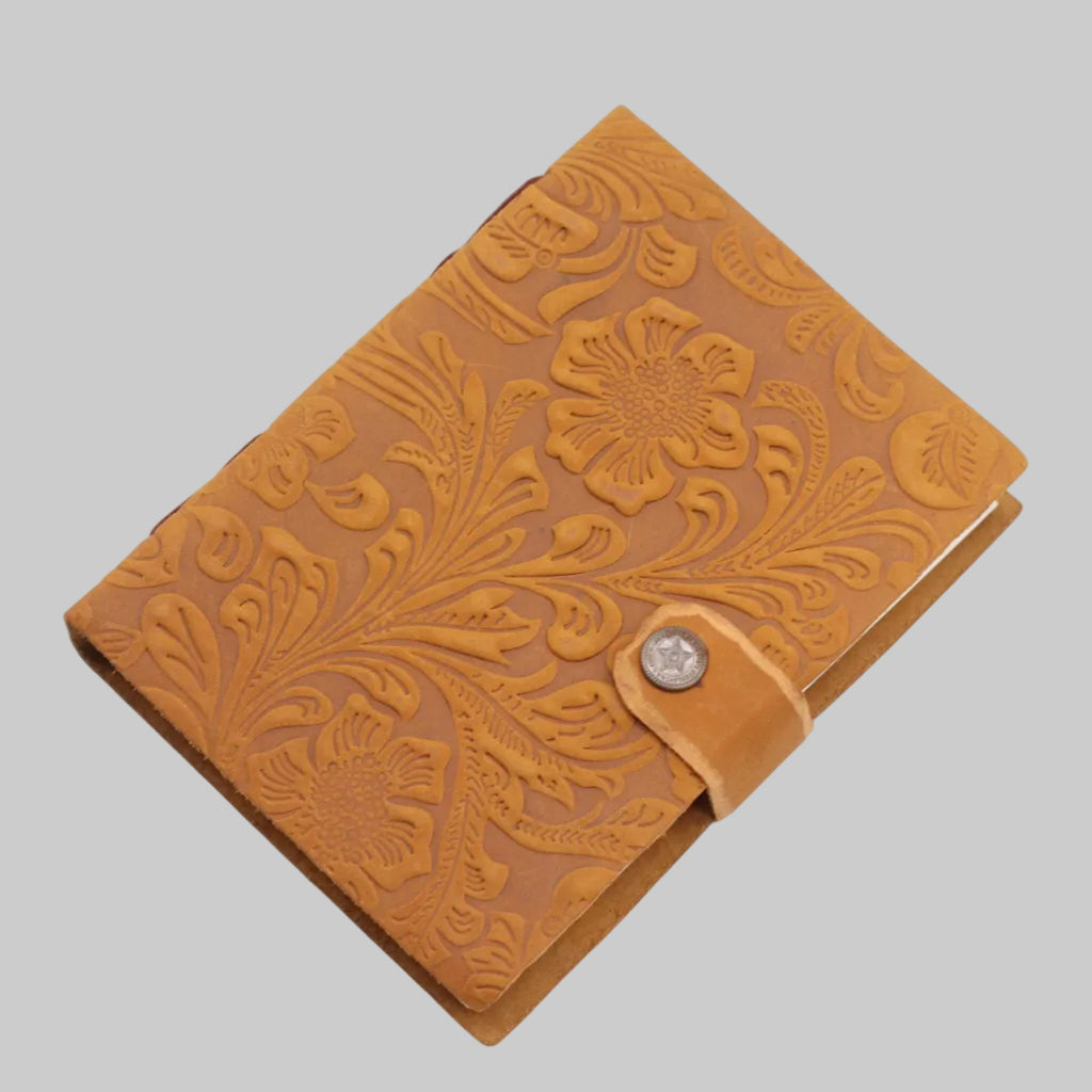 Brown leather notebook with floral embossing on a white background