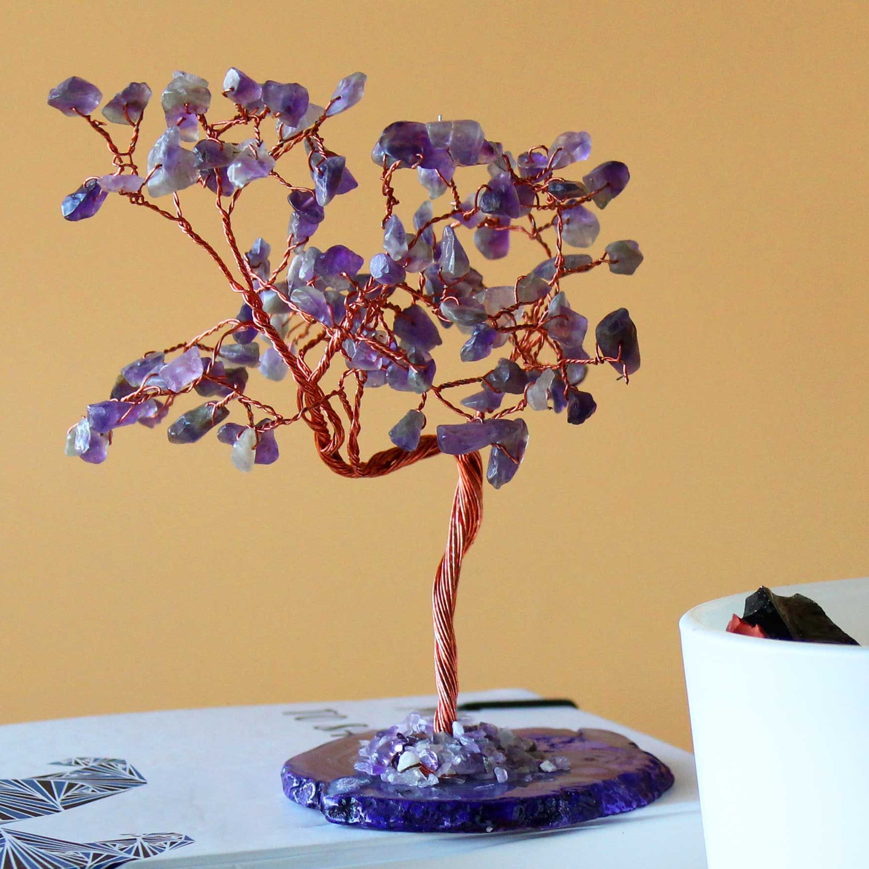 Decorative crystal tree on a book with a plain background