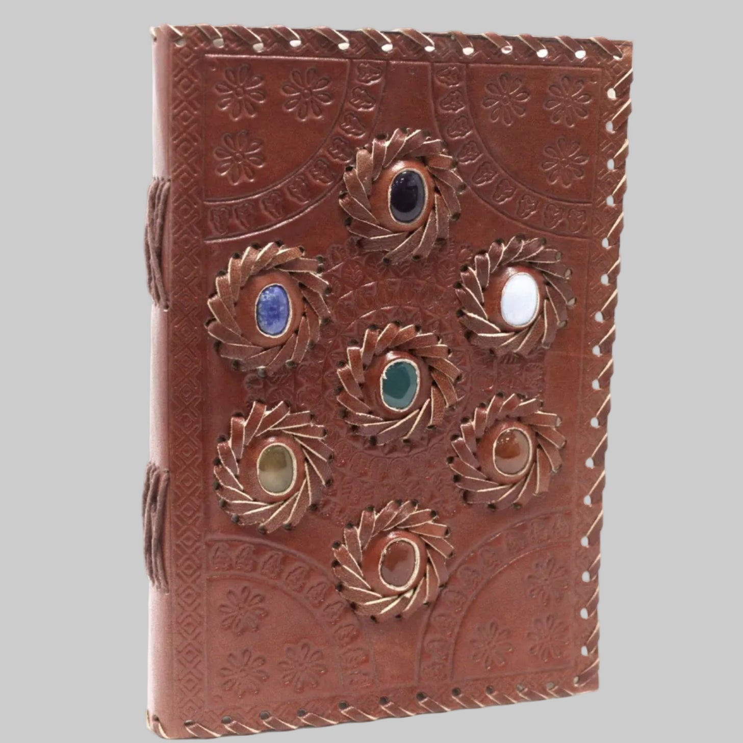 Brown leather journal with embossed designs and embedded stones on a white background