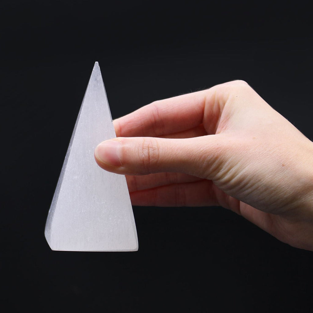 Hand holding a white cone-shaped object against a black background