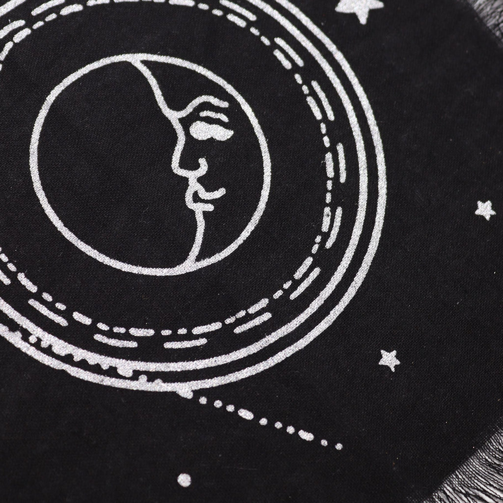 Black fabric with white embroidered design of a face within a circular pattern and stars.