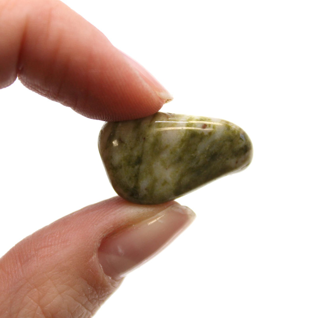 Hand holding a small greenish stone against a white background