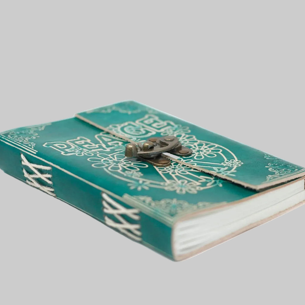 Green notebook with decorative cover and brass buckle on a white background