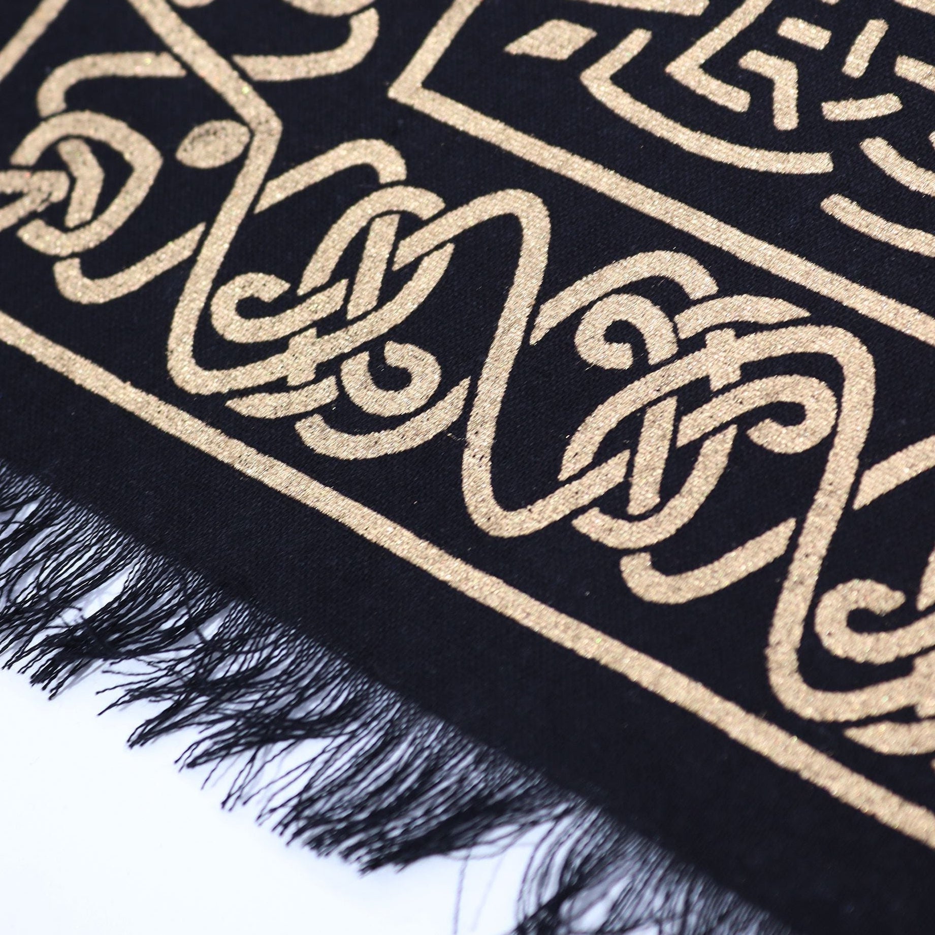 Black scarf with gold intricate patterns on a white background