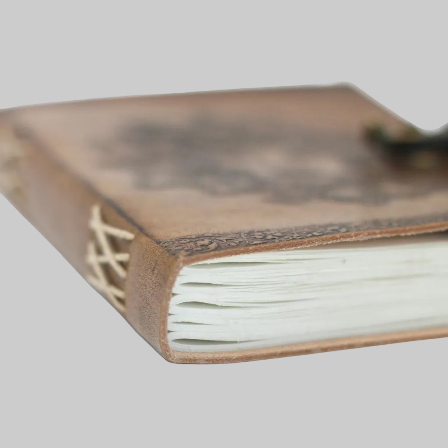 Close-up of a leather-bound notebook with white pages on a white background