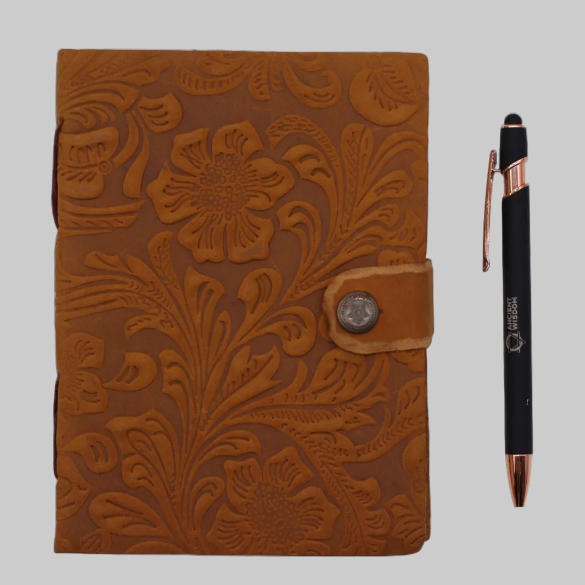 Brown floral embossed leather notebook with a pen on a white background
